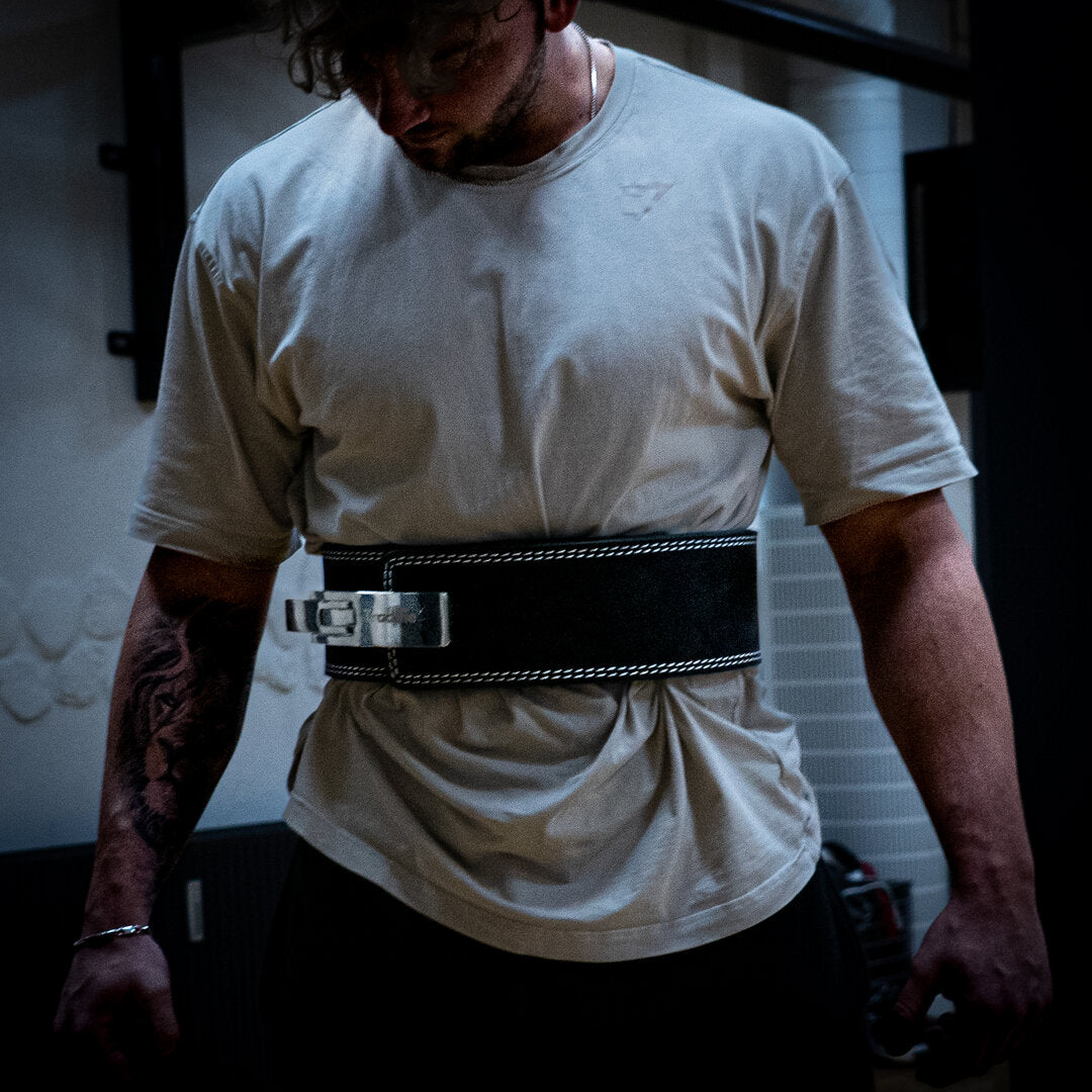 Mand med sort Trackfie træningsbælte kigger ned i gulvet i et træningscenter