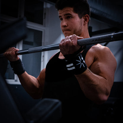 Mand i fitnesscenter laver curls med wrist wraps