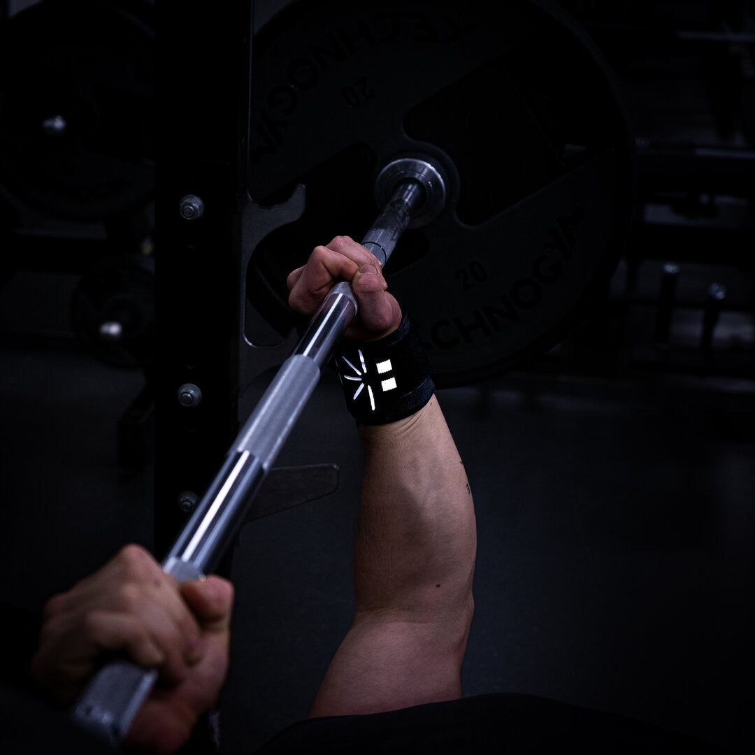 Mand bruger wrist wraps til at udføre bænkpres