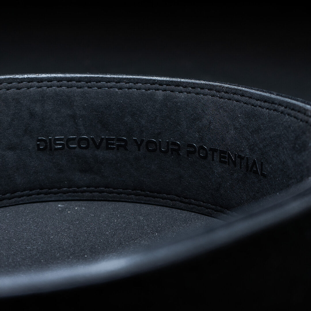 Indersiden af et sort Unlisted Strength lever belt med teksten 'discover your potential