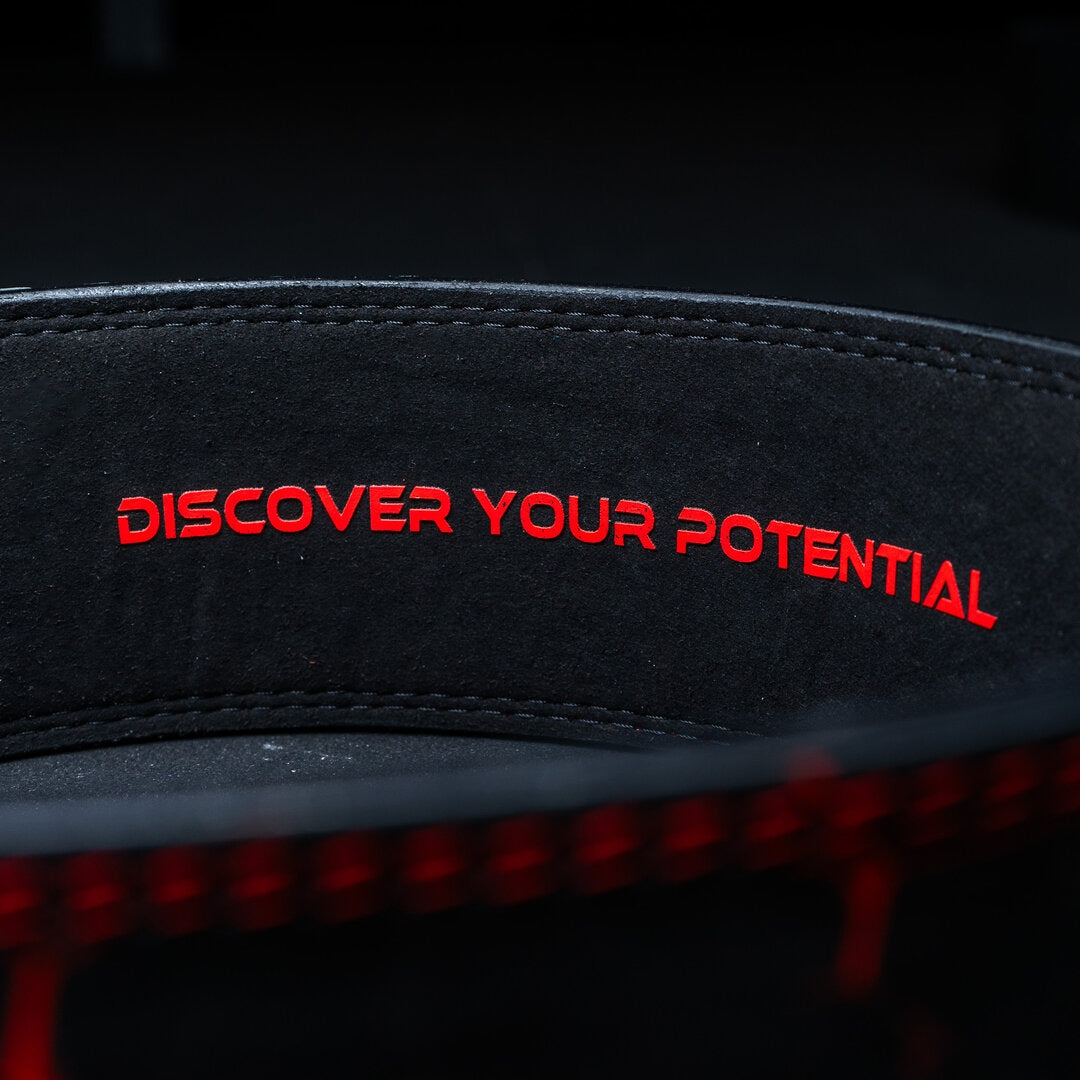 Indersiden af et rødt Unlisted Strength lever belt med teksten 'discover your potential'