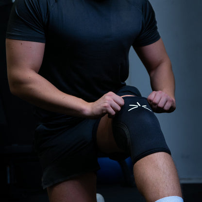 Mand trækker sine sorte trackfie knee sleeves op til sit knæ