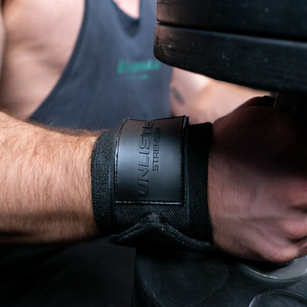 Nærbillede af sorte wrist wraps på en mand der sidder med dumbells