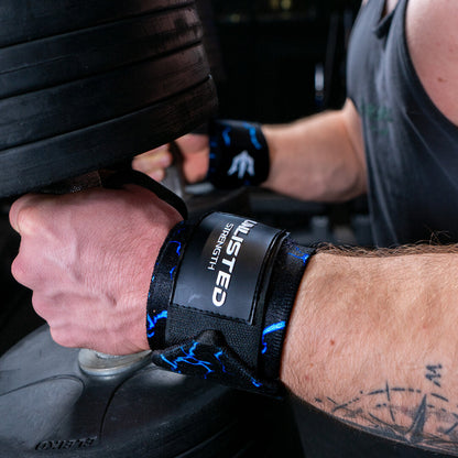 Nærbillede af blå wrist wraps på en mand der sidder med dumbbells