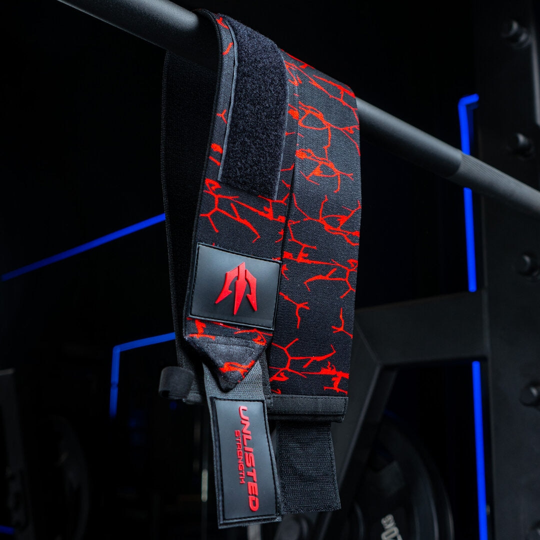 Røde Unlisted Strength wrist wraps der hænger ned fra barbell